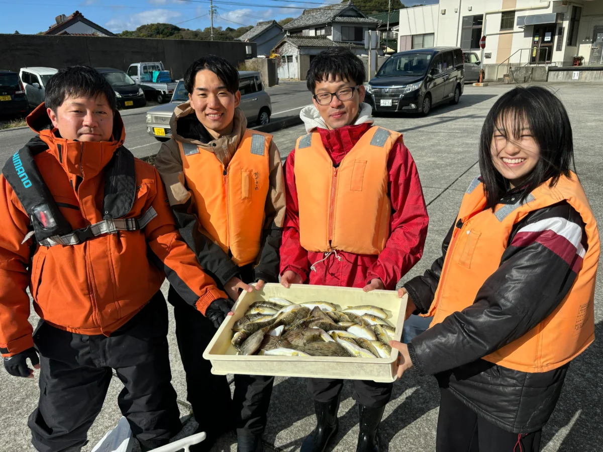 おざき丸のフグ釣りでお揃いのライフジャケットを着て大漁のフグを囲む、アットホームな雰囲気の若者グループ