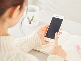 おざき丸への釣行予約を電話で行う際のイメージ(スマートフォンを操作する女性)